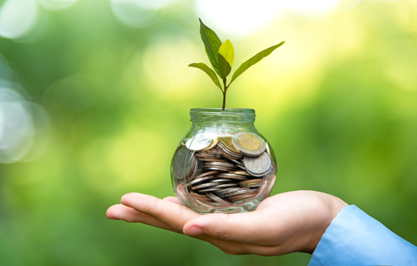 A person holding a jar filled with coins.