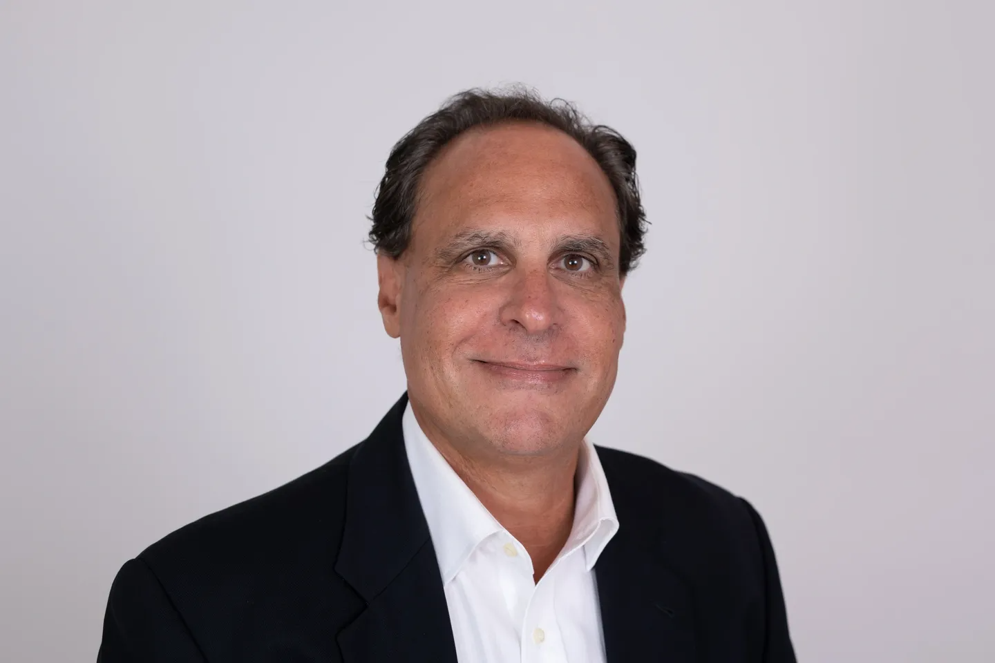 A man in a suit and tie smiling for the camera.