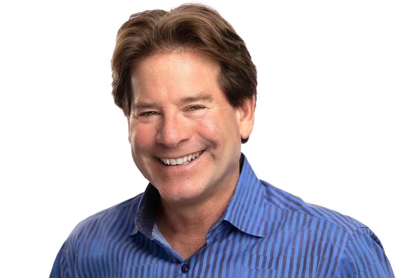 A man with brown hair and blue shirt smiling.